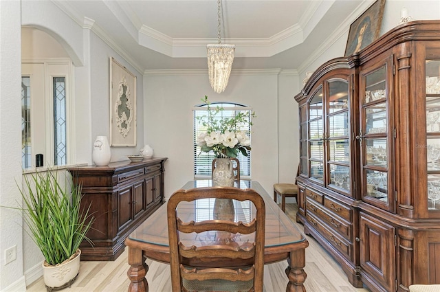 dining space featuring a raised ceiling, crown molding, and light hardwood / wood-style floors