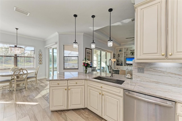 kitchen featuring sink, hanging light fixtures, stainless steel dishwasher, light stone countertops, and cream cabinets