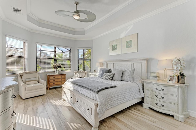 bedroom with a raised ceiling, crown molding, ceiling fan, and light wood-type flooring