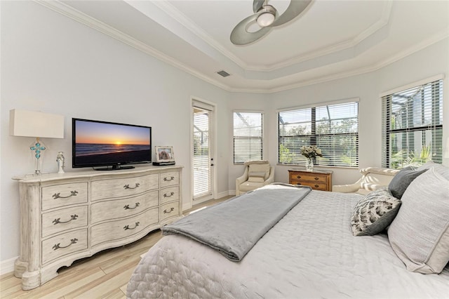 bedroom featuring crown molding, light hardwood / wood-style flooring, ceiling fan, a tray ceiling, and access to outside