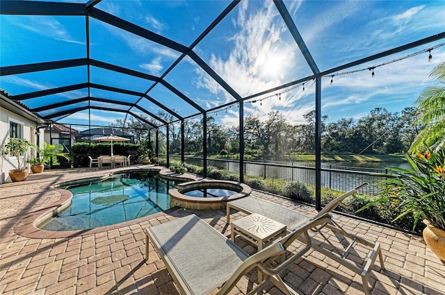 view of pool featuring an in ground hot tub, a water view, glass enclosure, and a patio