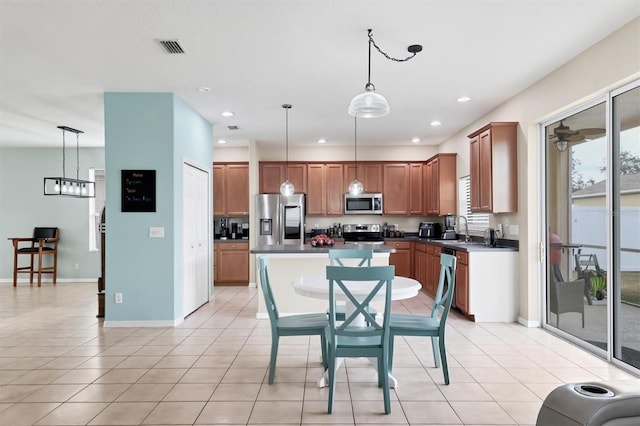 kitchen with light tile patterned flooring, stainless steel appliances, and decorative light fixtures