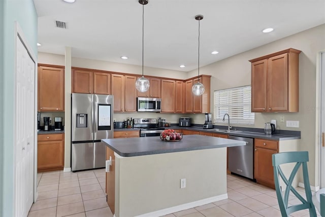 kitchen with sink, a center island, light tile patterned floors, appliances with stainless steel finishes, and pendant lighting