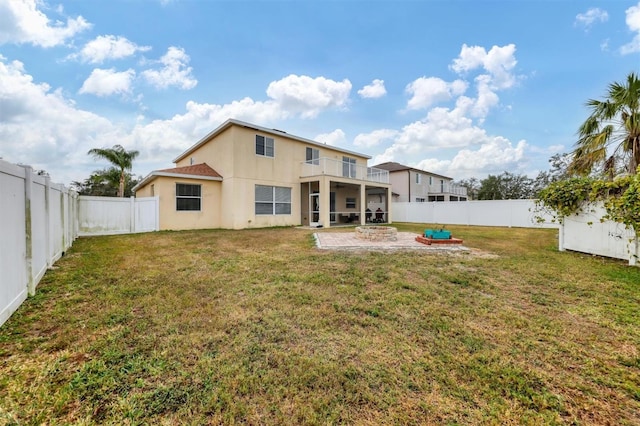 back of house featuring a balcony, an outdoor fire pit, and a lawn