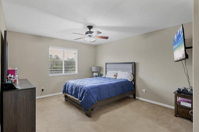 bedroom with ceiling fan, light colored carpet, and a textured ceiling