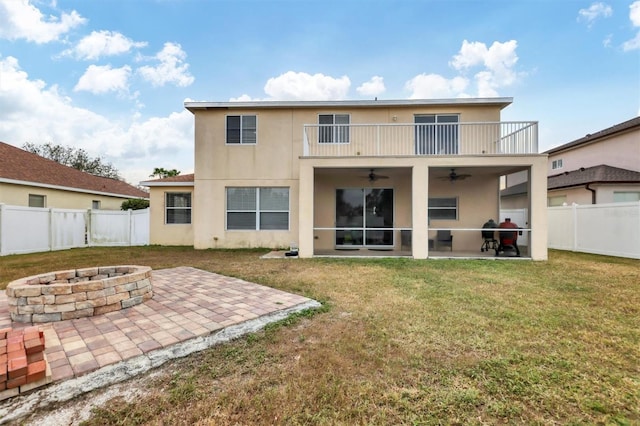 rear view of house with ceiling fan, an outdoor fire pit, a balcony, and a patio