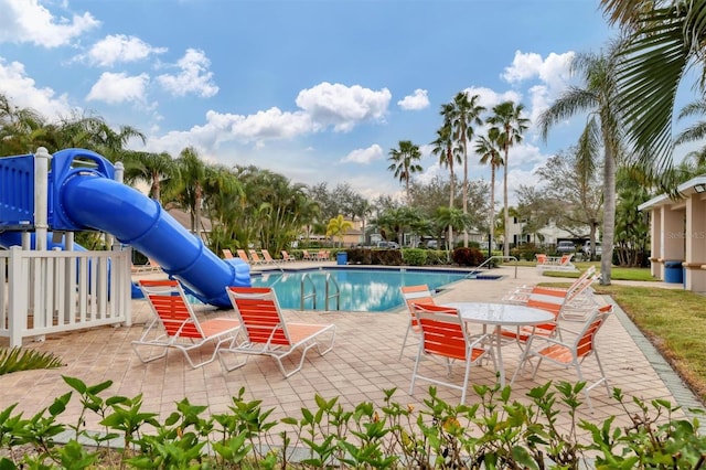 view of swimming pool featuring a playground, a patio, and a water slide