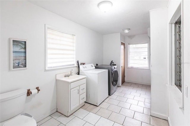 washroom with sink, light tile patterned floors, and washing machine and clothes dryer