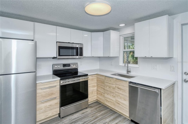 kitchen featuring sink, stainless steel appliances, white cabinets, and light hardwood / wood-style floors