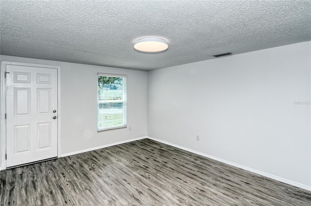 empty room featuring a textured ceiling and dark wood-type flooring