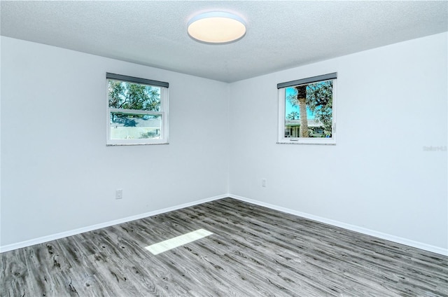 spare room with a textured ceiling and dark hardwood / wood-style floors