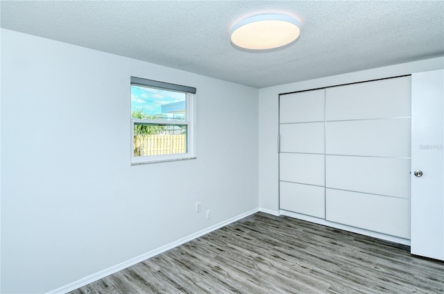 unfurnished bedroom featuring a textured ceiling, a closet, and hardwood / wood-style floors