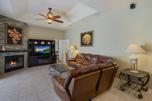 tiled living room with a tray ceiling, a fireplace, and ceiling fan