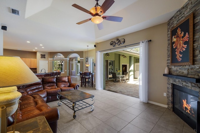 tiled living room featuring decorative columns, ceiling fan, and a fireplace