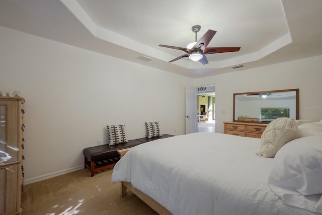 bedroom with light carpet, a raised ceiling, and ceiling fan