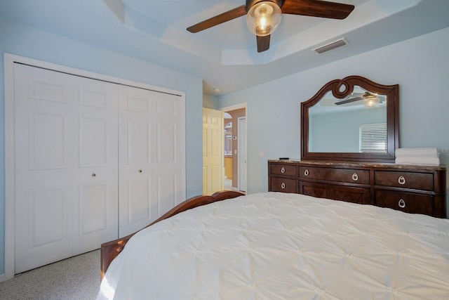 bedroom with ceiling fan, a tray ceiling, and a closet