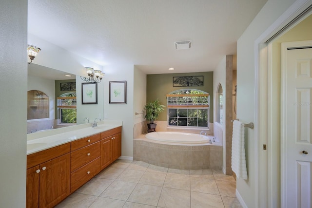 bathroom with tiled tub, vanity, and tile patterned floors