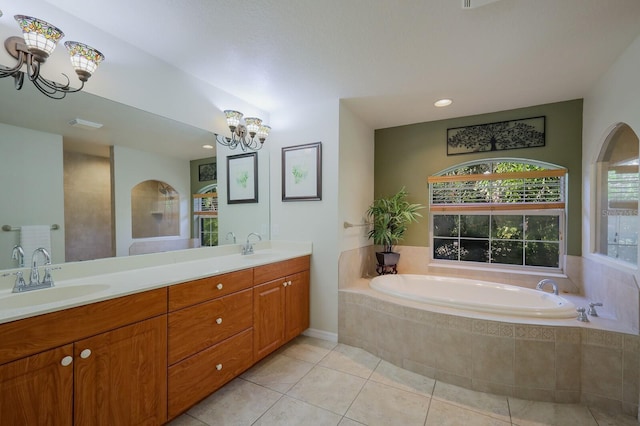 bathroom featuring an inviting chandelier, vanity, tile patterned flooring, and tiled bath