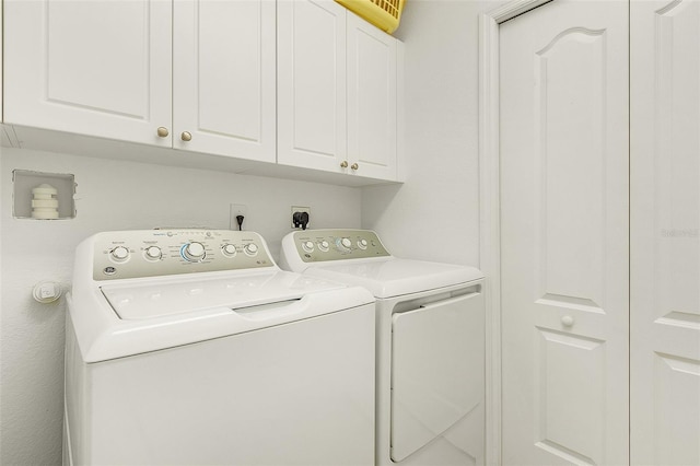 clothes washing area with cabinets and washing machine and clothes dryer