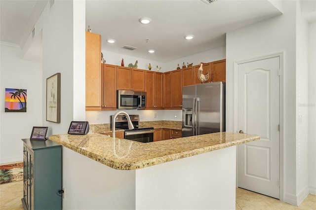 kitchen with light stone countertops, appliances with stainless steel finishes, light tile patterned floors, and kitchen peninsula