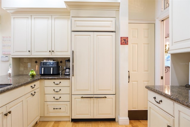 kitchen featuring dark stone counters, light hardwood / wood-style floors, and decorative backsplash