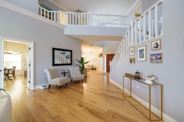 interior space featuring hardwood / wood-style flooring, a towering ceiling, a notable chandelier, and ornamental molding