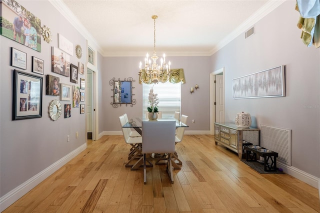 dining room featuring crown molding, light hardwood / wood-style floors, and an inviting chandelier