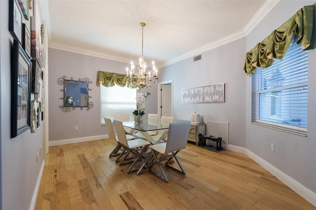 dining space featuring crown molding, light hardwood / wood-style flooring, a textured ceiling, and a notable chandelier