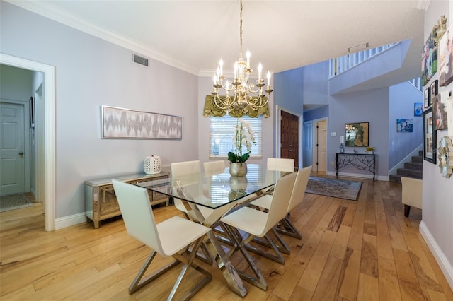 dining space with crown molding, a chandelier, and light hardwood / wood-style flooring