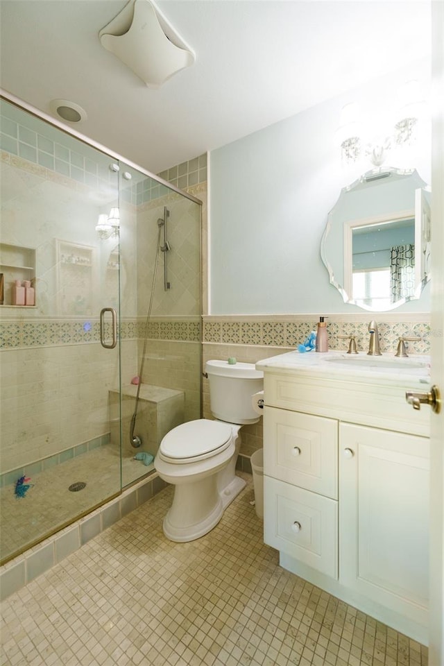 bathroom featuring a shower with door, toilet, vanity, and tile walls