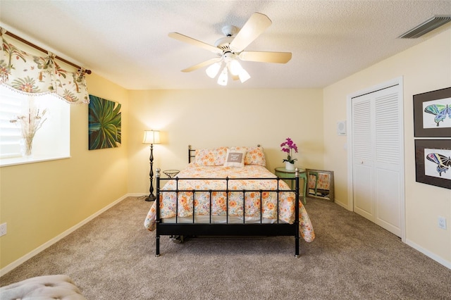 bedroom with a closet, ceiling fan, carpet flooring, and a textured ceiling