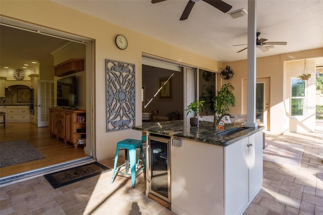 kitchen featuring sink, white cabinetry, dark stone counters, and wine cooler