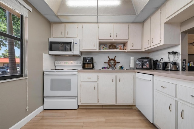 kitchen with white cabinetry, backsplash, and white appliances