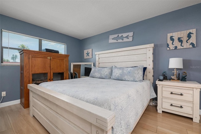 bedroom with light wood-type flooring and a textured ceiling