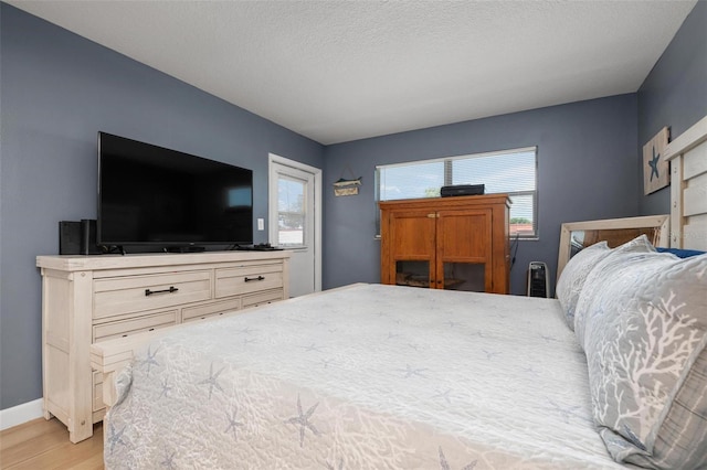 bedroom with light hardwood / wood-style flooring and a textured ceiling