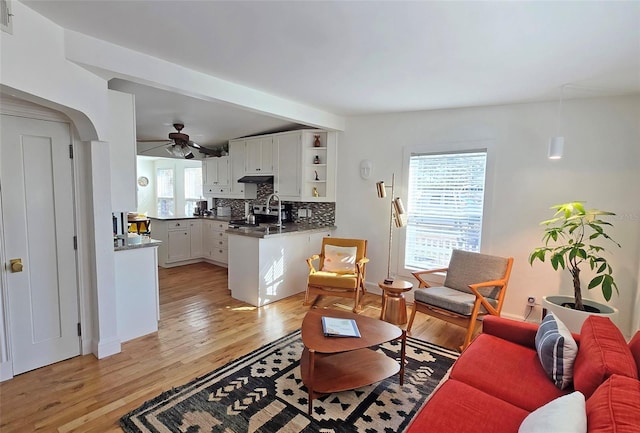 living room with ceiling fan, sink, and light hardwood / wood-style floors