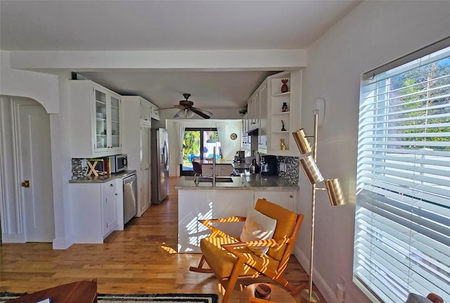 kitchen with white cabinetry, wood-type flooring, sink, light stone counters, and stainless steel appliances