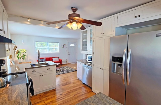 kitchen featuring sink, dark stone countertops, light wood-type flooring, stainless steel appliances, and white cabinets