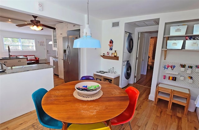 dining space with ceiling fan, stacked washer and clothes dryer, and light hardwood / wood-style floors