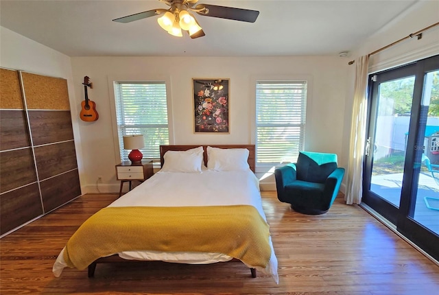 bedroom with hardwood / wood-style flooring, ceiling fan, access to exterior, and multiple windows