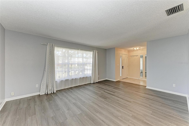 spare room featuring light hardwood / wood-style flooring and a textured ceiling