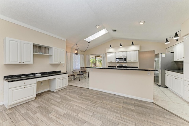 kitchen featuring stainless steel appliances, a kitchen island with sink, built in desk, and white cabinets