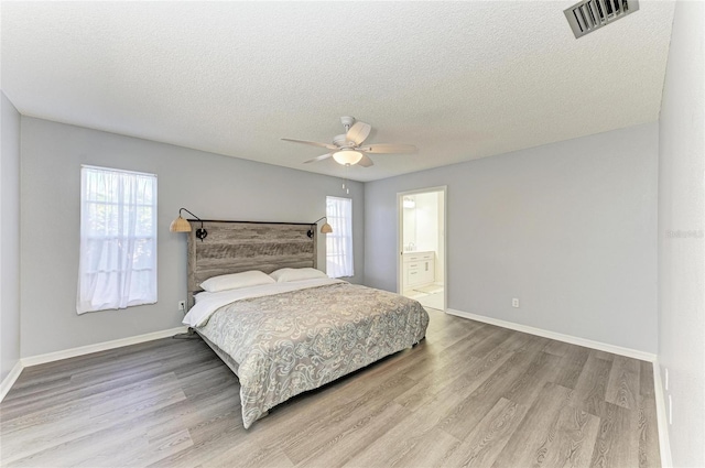 bedroom with multiple windows, wood-type flooring, and a textured ceiling