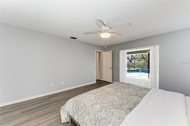 bedroom featuring access to exterior, dark wood-type flooring, a textured ceiling, and ceiling fan