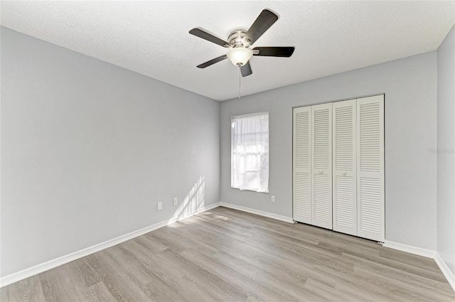 unfurnished bedroom featuring ceiling fan, a textured ceiling, light hardwood / wood-style floors, and a closet