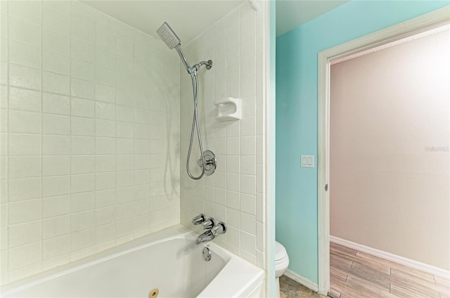 bathroom with toilet and tiled shower / bath