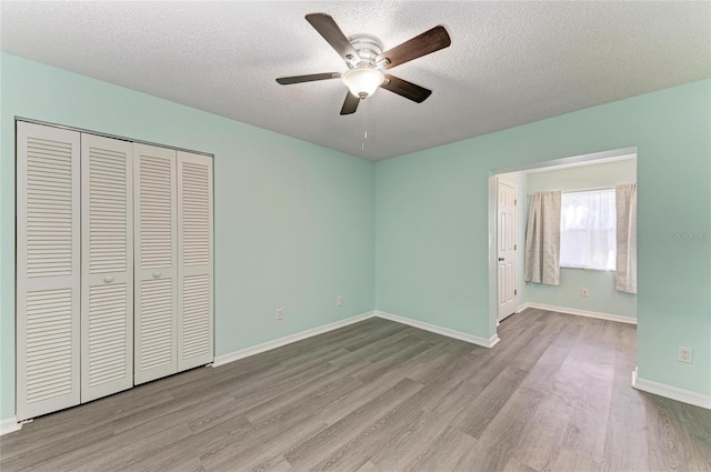 unfurnished bedroom featuring a closet, a textured ceiling, and light wood-type flooring