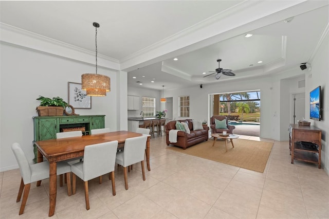 dining area with light tile patterned flooring, a healthy amount of sunlight, ornamental molding, and a tray ceiling