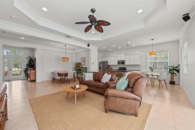living room with crown molding, light tile patterned floors, and a raised ceiling