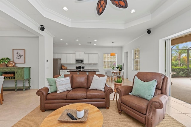living room featuring light tile patterned floors, a tray ceiling, and ornamental molding